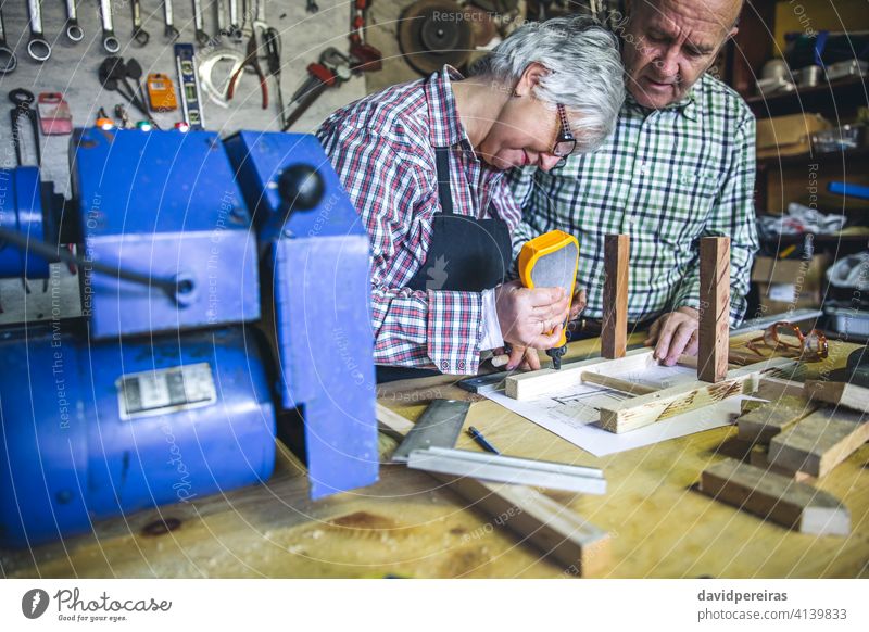 Seniorenpaar in einer Tischlerei Schreinerei Frau Kleben Stuhl diy Zimmerer benutzend Leim Paar Möbel Werkstatt arbeiten Holz reif Business Kaukasier Ruhestand