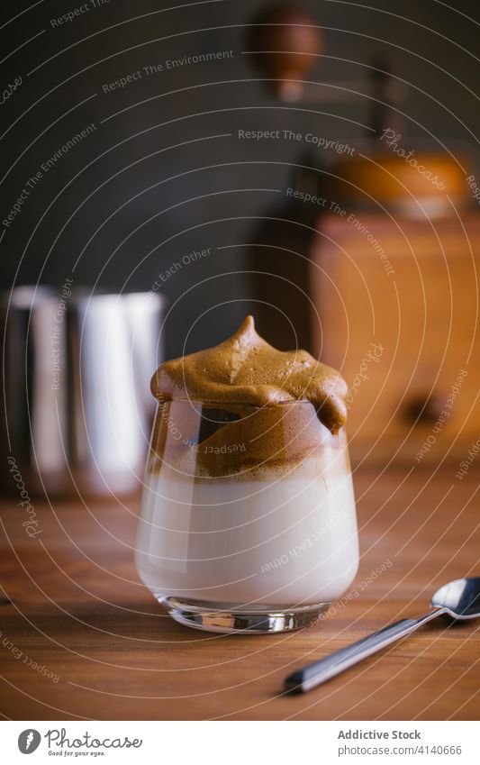 Dalgona Kaffee und Kaffeemühle im Holztisch dalgona-kaffee gepeitscht melken geschmackvoll kalt Erfrischung Tisch Kaffeelöffel trinken sofort hinzufügen lecker