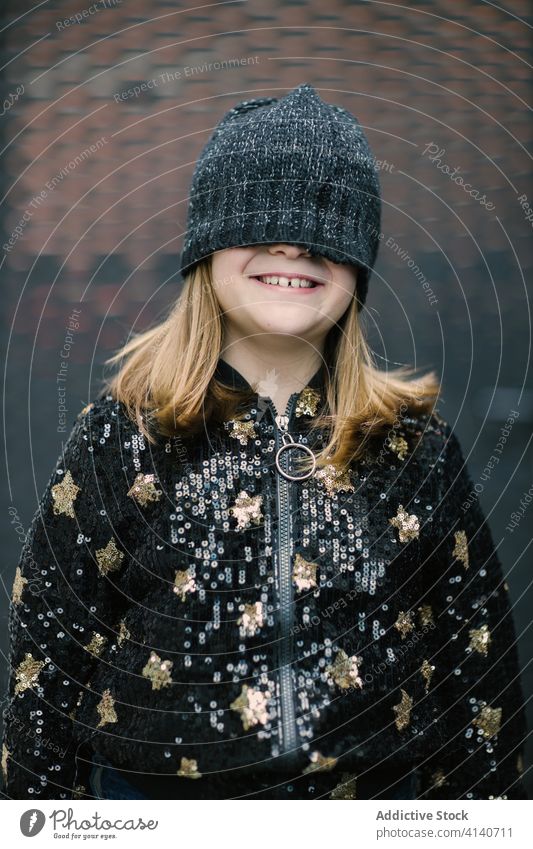 Unerkennbar lächelndes Mädchen mit warmer Mütze, die das halbe Gesicht bedeckt Spaß Verschlussdeckel Kindheit warme Kleidung Gesicht machen Freizeit Erholung