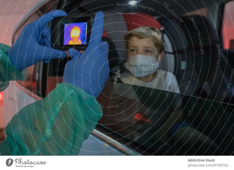 Arzt in Latexhandschuhen prüft Temperatur mit Wärmekamera messen Junge Infrarotaufnahme Fotokamera thermisch Coronavirus prüfen Seuche Bund 19 Scan Ausbruch
