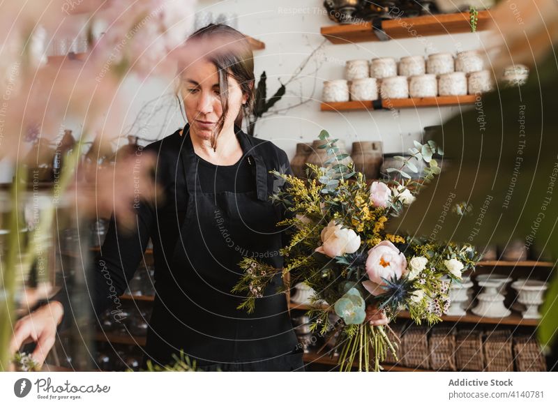 Weibliche Designerin entwirft Blumensträuße im Atelier Floristik Frau Blumenstrauß einrichten kreieren Blütezeit komponieren dekorativ kreativ Arbeit Beruf