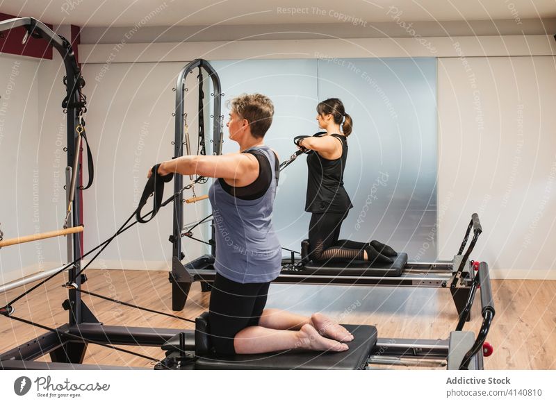 Sportliche Frauen beim Training auf Pilates-Reformern Sportlerinnen Maschine Übung Zusammensein sportlich widersetzen Aktivität Sportkleidung Metall Gerät
