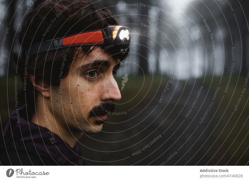 Seriöser männlicher Läufer mit Stirnlampe im dunklen Wald Nebel Sportler Taschenlampe Wälder Training Holz Athlet Gesundheit stehen Sportbekleidung Natur Übung