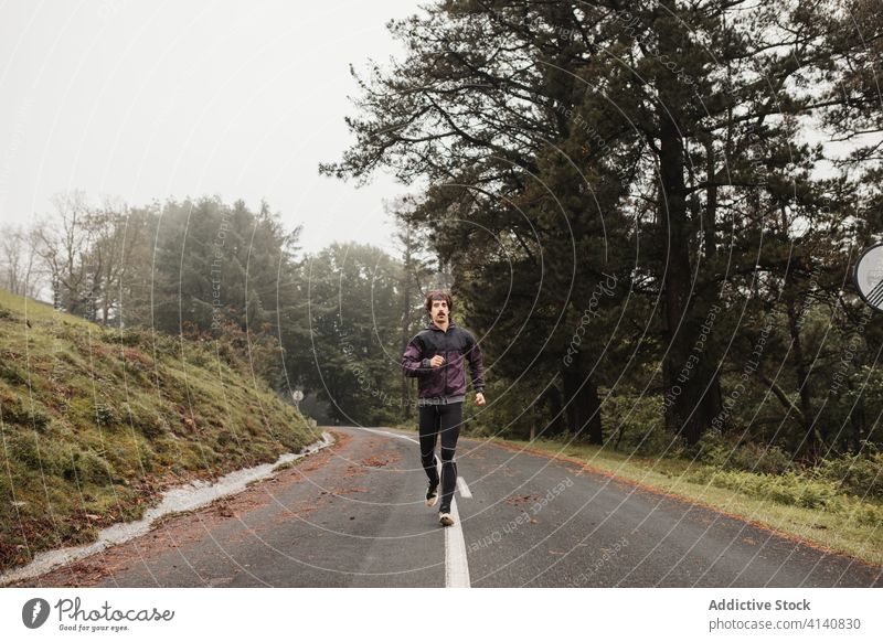 Sportler läuft auf leerer Straße Läufer laufen Morgen Nebel Training Herz Sportbekleidung männlich Asphalt grün Athlet Übung Gesundheit Baum Ausdauer Aktivität