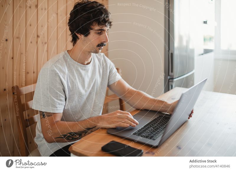 Mann tippt bei der Fernarbeit auf einem Laptop Projekt freiberuflich Arbeit Tippen benutzend Inhalt Unternehmer Inbetriebnahme männlich gemütlich Tisch Küche