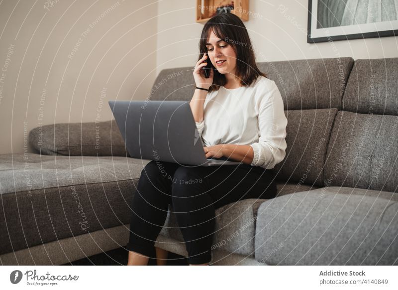 Freiberuflerin, die zu Hause mit ihrem Smartphone spricht und einen Laptop benutzt multitask Unternehmer Frau benutzend Apparatur Projekt reden Browsen