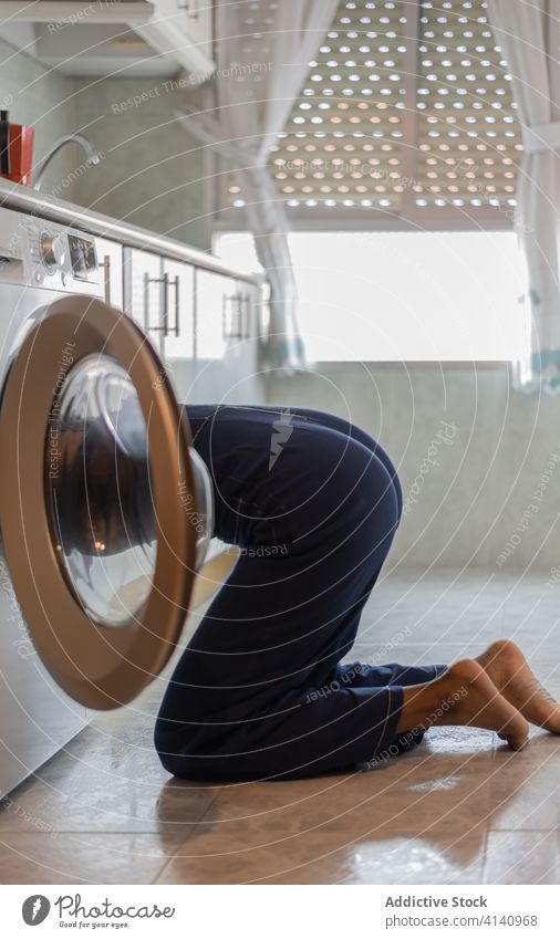 Ethnische Frau beim Beladen der Waschmaschine zu Hause Wäscherei Waschen Maschine Hausfrau heimwärts Küche heimisch Arbeit ethnisch Windstille Sauberkeit
