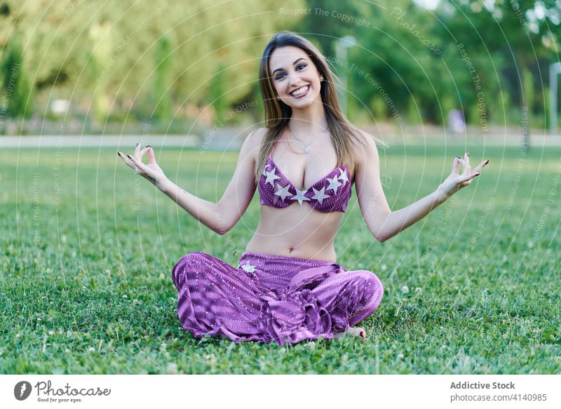 Ruhige Frau im Bauchtanzkostüm meditiert im Park Yoga Lotus-Pose meditieren Gelassenheit Harmonie sich[Akk] entspannen heiter padmasana ethnisch Tänzer Tracht