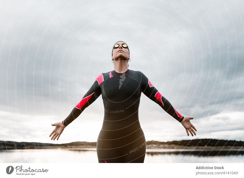Anonyme Sportlerin auf hohem Felsen am See Frau Neoprenanzug Taucher Wasser Felsbrocken Abend Inspiration Sonnenuntergang Badeanzug Natur Ufer