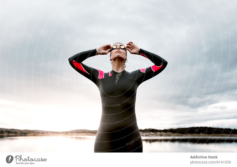 Frau im Taucheranzug mit Brille am Seeufer Neoprenanzug Schutzbrille Badeanzug Ufer extrem Umwelt Schwimmer aqua sportlich reisen Bestimmen Sie schwimmen
