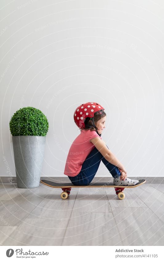 Glückliches Mädchen im Vorschulalter fährt zu Hause Skateboard heimwärts Spiel unterhalten Spaß Kind spielen Dekor Longboard Schutzhelm träumen zu Hause bleiben