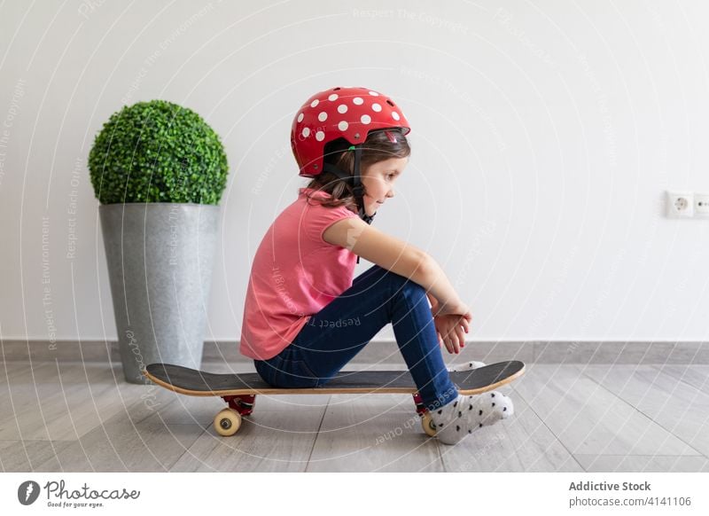 Glückliches Mädchen im Vorschulalter fährt zu Hause Skateboard heimwärts Spiel unterhalten Spaß Kind spielen Dekor Longboard Schutzhelm träumen zu Hause bleiben