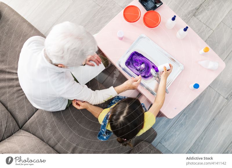 Großvater und Großmutter bereiten zu Hause bunten Schleim mit Tinte zu Enkelin Spaß machen Tusche diy Kunst Handwerk hinzufügen Farbstoff Aktivität Generation