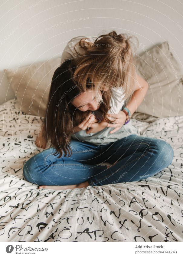 Teenager-Mädchen kitzelt kleine Schwester auf dem Bett Kribbeln Lachen spielen spielerisch Spaß haben Spiel Wochenende Zusammensein heiter heimwärts Glück