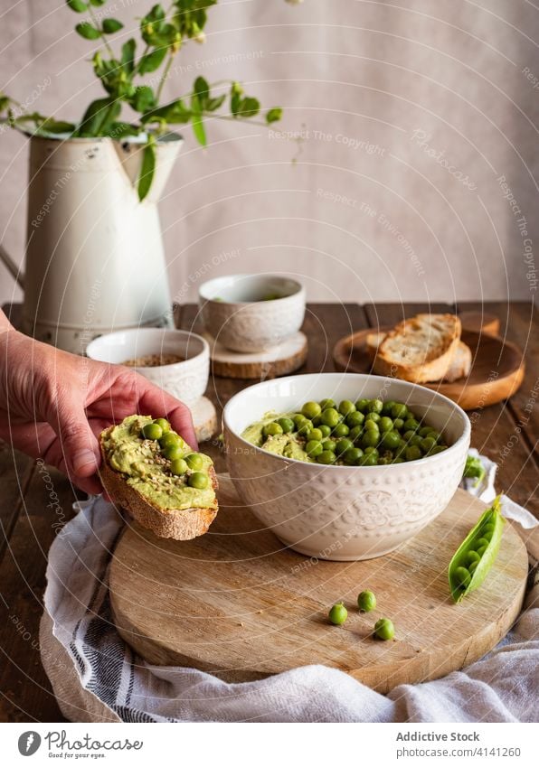 Unbekannte Person isst Brot mit Hummus Erbse Lebensmittel Hand essen grün natürlich geschmackvoll Amuse-Gueule Anlasser dienen Koch frisch Ernährung Gesundheit