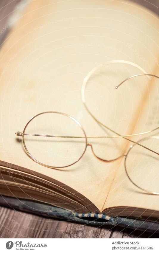 Aufgeschlagenes Buch mit Brille auf dem Tisch offen Antiquität altmodisch hölzern retro schäbig altehrwürdig Schreibtisch kreativ Bibliothek Sammlung Lehrbuch