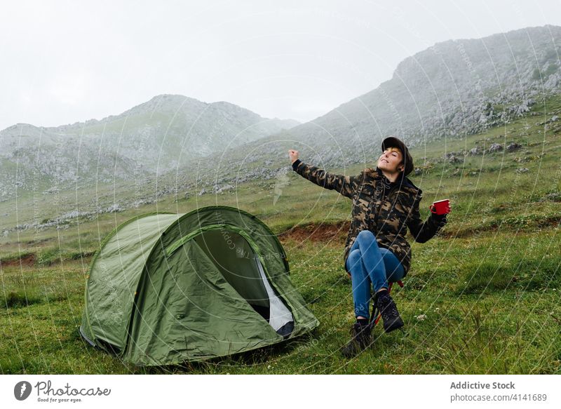Frau in Oberbekleidung streckt Körper in der Nähe von Camping-Zelt in der Natur Dehnung Lager Hochland Inhalt sich[Akk] entspannen Reisender Morgen Fernweh