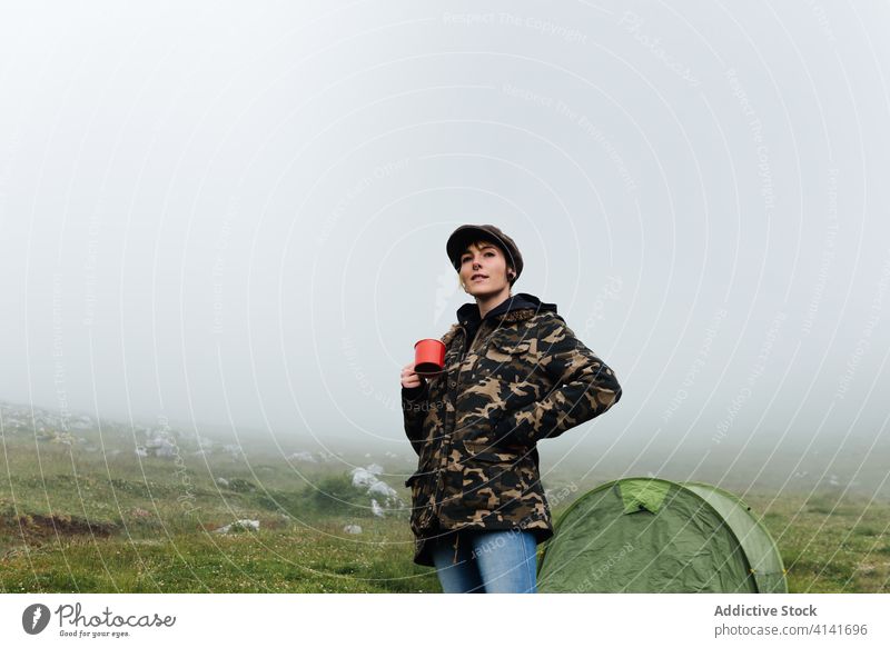 Frau in Oberbekleidung in der Nähe eines Campingzeltes in der Natur Lager Zelt Hochland Inhalt sich[Akk] entspannen Reisender stehen Morgen Nebel Fernweh