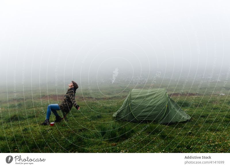 Frau in Oberbekleidung in der Nähe eines Campingzeltes in der Natur Lager Zelt Hochland Inhalt sich[Akk] entspannen Reisender Morgen Fernweh Freiheit Landschaft