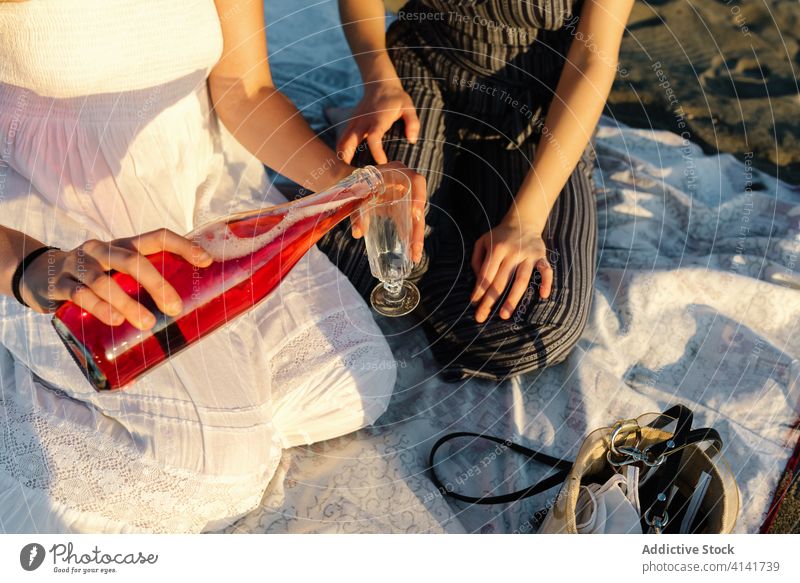 Ein Paar Frauen gießt Wein in ein Glas lesbisch Picknick eingießen Strand feiern lgbt Feiertag Alkohol trinken Zusammensein Getränk genießen Urlaub romantisch