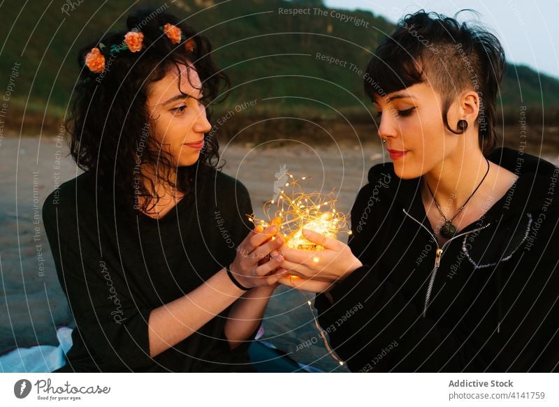 Verliebtes lesbisches Paar mit leuchtender Girlande am Strand Freundin glühen berühren Liebe lgbt Homosexualität sanft Zuneigung ruhen Partnerschaft romantisch