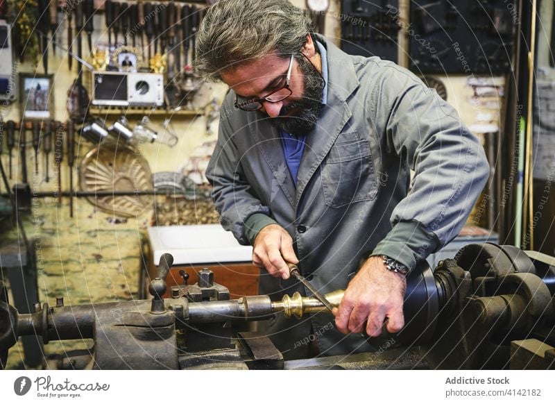 Konzentrierter Goldschmied mit Schleifmaschine in der Werkstatt Kunsthandwerker Schärfen Maschine Basteln Metall kleben Prozess Uniform Kleinunternehmen Beruf