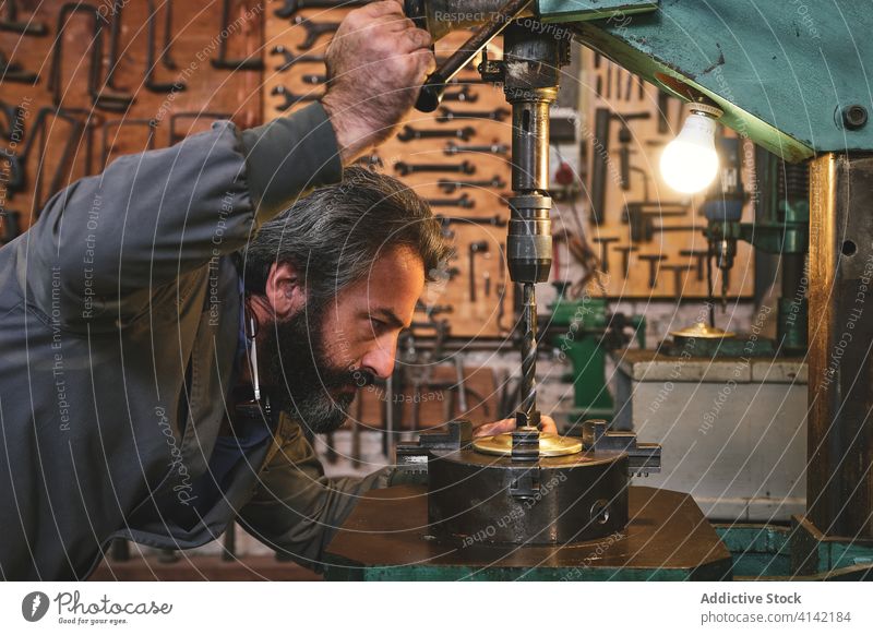 Älterer Juwelier bei der Arbeit an einer Graviermaschine in der Werkstatt Gravur Maschine Kunsthandwerker Metall Basteln Prozess Kleinunternehmen Kunstgewerbler