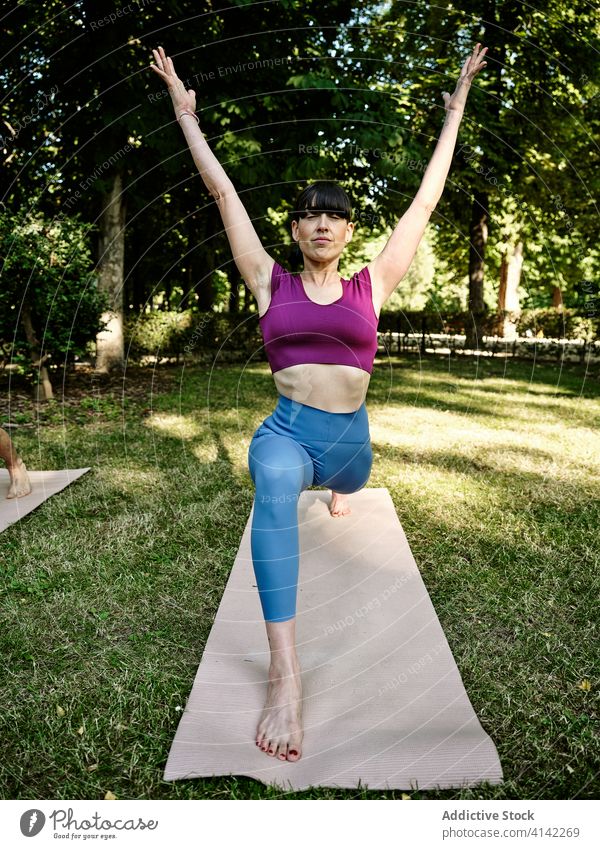 Ruhige Frau übt Yoga in Halbmondstellung Halbmondvariation Ausfallschritt hohe Longe Park Barfuß sonnig Training Augen geschlossen ruhig Gesundheit Gelassenheit
