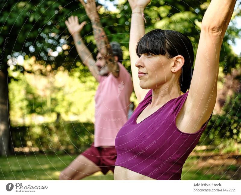 Ruhiges Paar übt Yoga in Halbmond-Pose zusammen Halbmondvariation Ausfallschritt hohe Longe Zusammensein Park Barfuß sonnig Training Partnerschaft ruhig