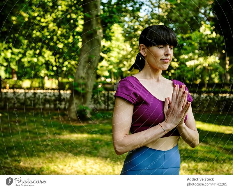 Frau beim Yoga in Bergpose Berg-Pose tadasana Namaste Asana sich[Akk] entspannen Gebetshände Augen geschlossen üben ruhig Gesundheit meditieren Park Harmonie