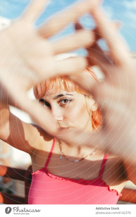 Junge Frau mit rosa Haaren in der Stadt tausendjährig sorgenfrei anders Verhalten expressiv Stadtbild Grimasse kreativ modern trendy gestikulieren Stil Spaß