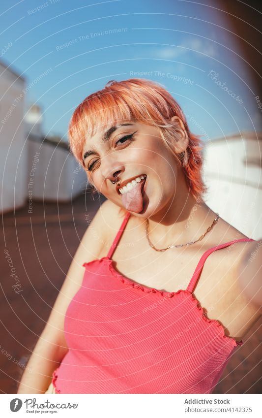 Junge Frau mit rosa Haaren in der Stadt tausendjährig Gesicht machen sorgenfrei anders Verhalten expressiv Stadtbild Grimasse kreativ modern trendy