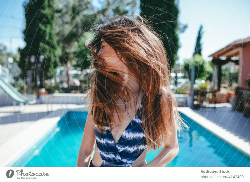 Zufriedene Frau im Badeanzug am Pool fliegendes Haar Sommer Urlaub sorgenfrei Beckenrand Badebekleidung Inhalt sonnig sich[Akk] entspannen ruhen Feiertag heiter