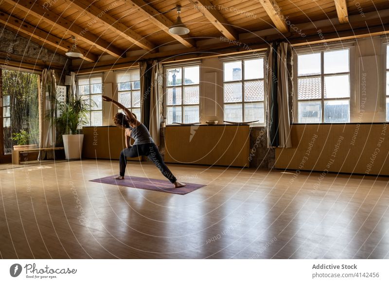 Schlanke Frau übt Yoga im geräumigen Studio üben Asana umgekehrte Krieger-Pose positionieren beweglich schlank Wegbiegung Gesundheit Konzentration Wellness