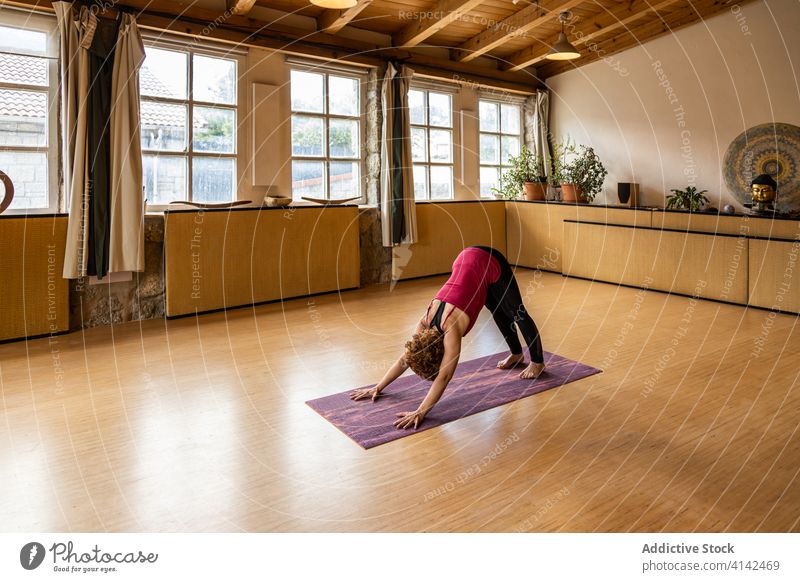 Schlanke Frau übt Yoga im geräumigen Studio üben Asana nach unten gerichteter Hund Pose positionieren beweglich schlank Wegbiegung Gesundheit