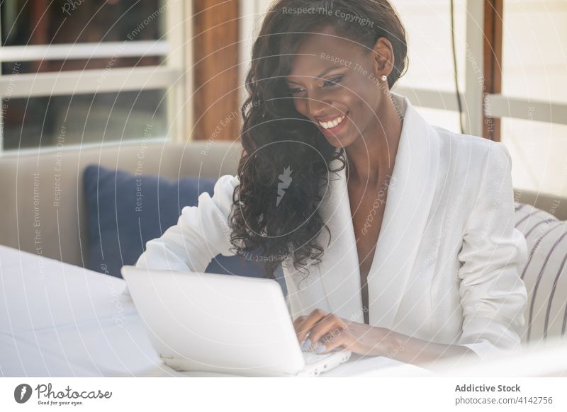 Schwarze Frau benutzt Netbook, während sie alleine arbeitet Geschäftsfrau Laptop unabhängig benutzend abgelegen elegant freiberuflich Arbeitsplatz professionell