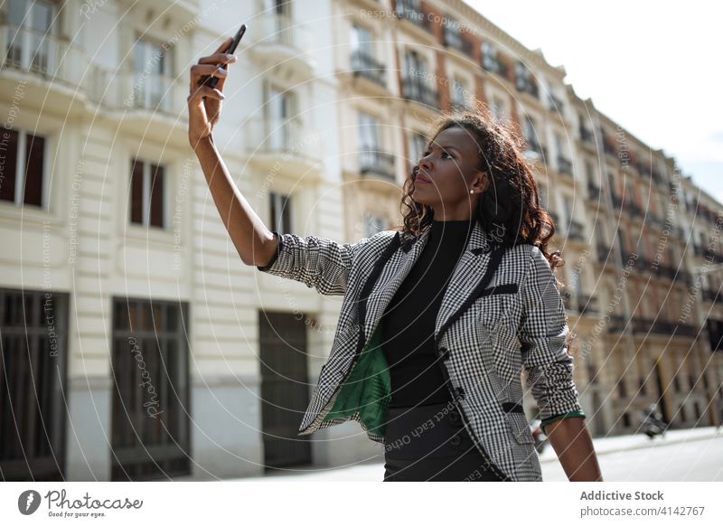 Junge Frau im schicken Anzug nimmt Selfie auf der Straße Geschäftsfrau Smartphone Großstadt urban formal selbstbewusst jung Afroamerikaner schwarz ethnisch