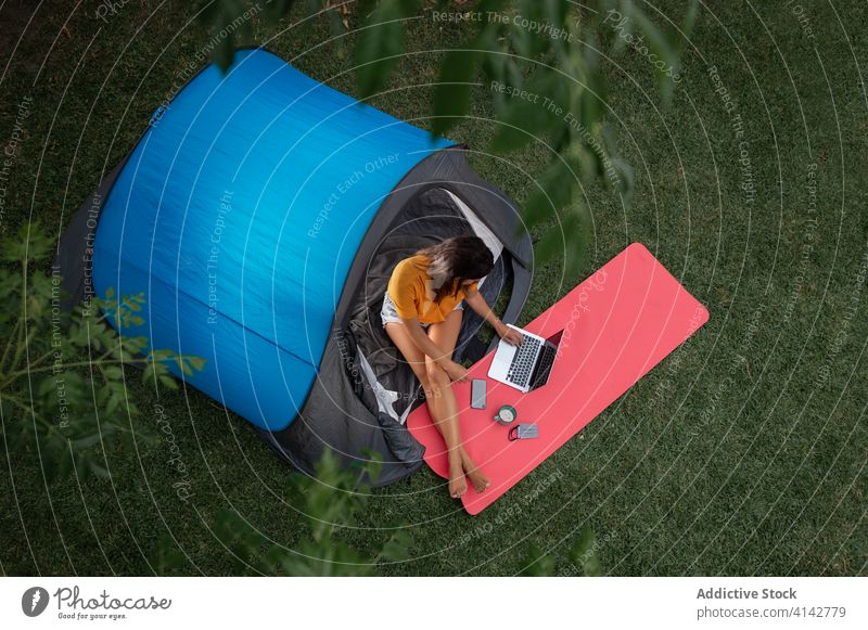 Junge Frau benutzt Geräte beim Camping Lager Apparatur benutzend modern Zelt Tourist positiv Natur jung lässig Laptop Wiese ruhen Urlaub sich[Akk] entspannen
