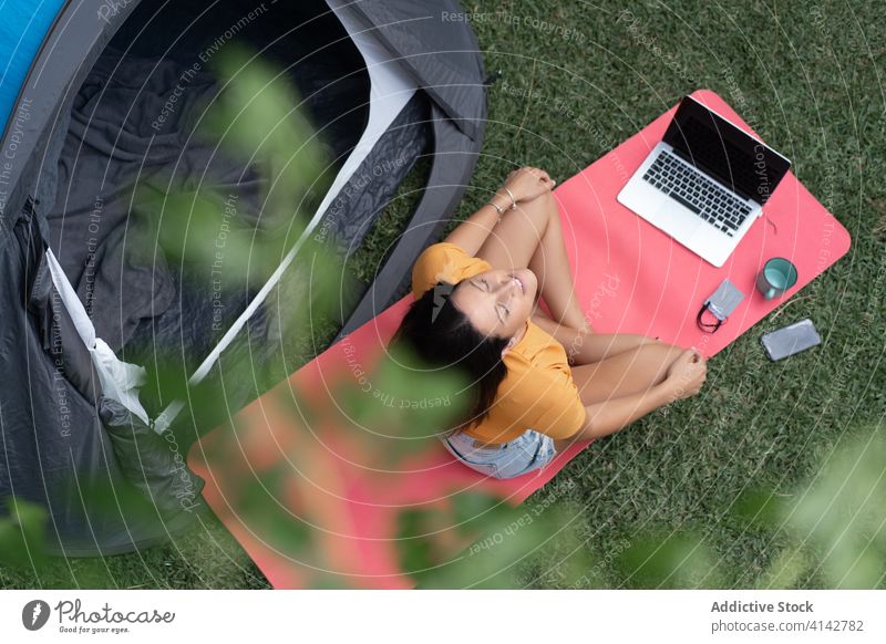 Glückliche Frau mit Gadgets, die sich in der Nähe eines Touristenzeltes ausruhen Lager sich[Akk] entspannen Sommer genießen Apparatur modern Zelt Natur