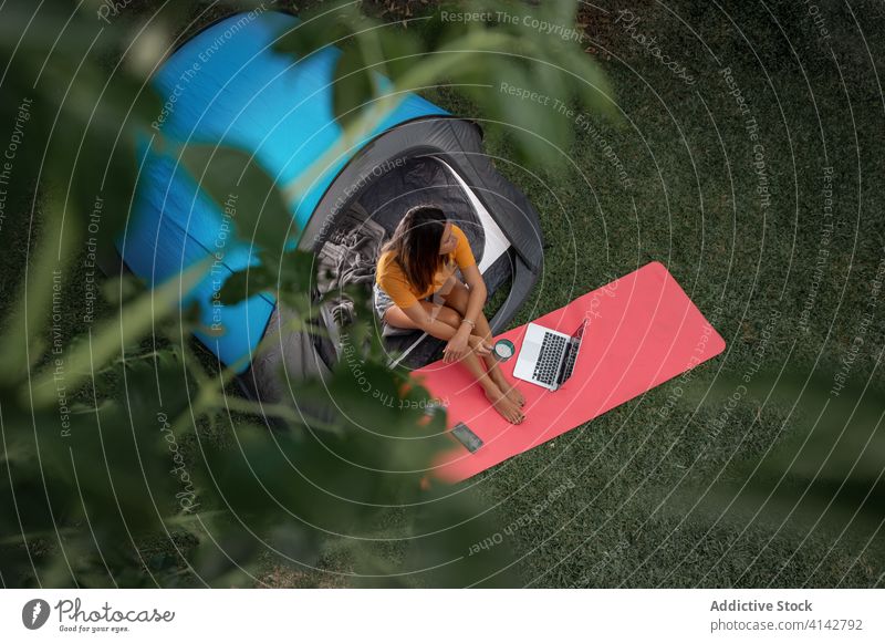 Junge Frau benutzt Geräte beim Camping Lager Apparatur benutzend modern Zelt Tourist positiv Natur jung lässig Laptop Wiese ruhen Urlaub sich[Akk] entspannen