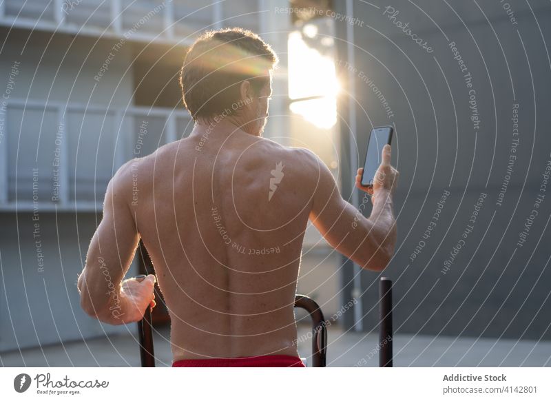 Starker Mann beim Training auf dem Stepper Selfie Smartphone muskulös stark benutzend ohne Hemd männlich Athlet Hof Sport Gesundheit Körper aktiv Energie