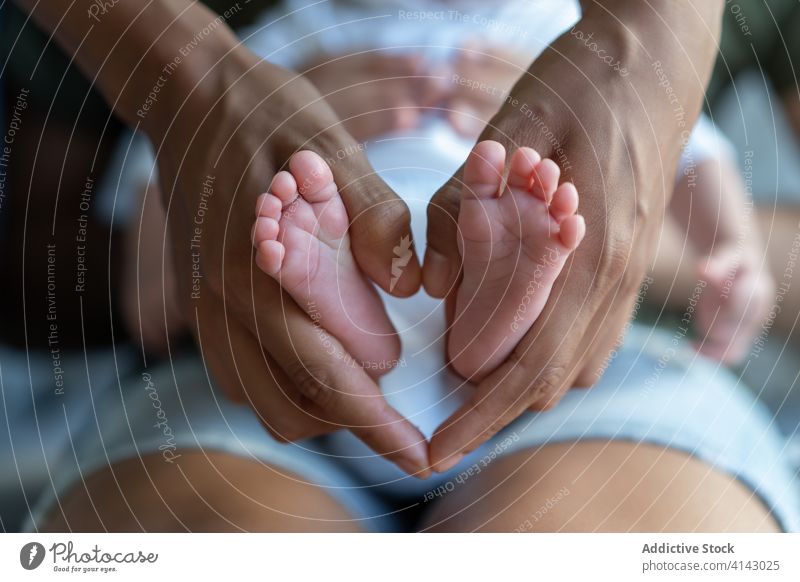 Crop-Frau mit Füßen eines Säuglings Baby Fuß winzig Mutter neugeboren Angebot Eltern Familie Herz ethnisch Form Liebe klein wenig Zusammensein Pflege Kind