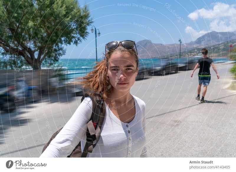 Selfie einer schönen jungen Frau im Urlaub Rücken Rucksack blau Unschärfe Junge Autos lässig Kaukasier selbstbewusst Laufwerk Außenseite Mädchen wandern Reise