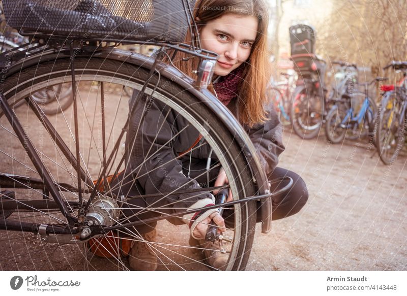 Junge Frau pumpt die Reifen ihres Fahrrads auf Aktivität Air lässig Kaukasier Nahaufnahme selbstbewusst hockend Details Gerät fixieren Mädchen Lifestyle Makro
