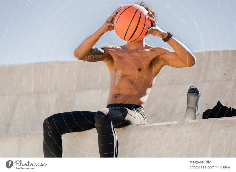 Afro-Athletischer Mann beim Entspannen nach dem Training. Sport Basketball Ball urban sportlich im Freien Stehen genießen Ausdruck aktiv Hand Übung Erholung