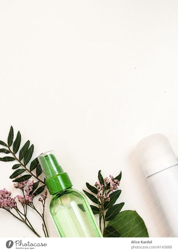 Kosmetikprodukte  für die Körperpflege liegen auf einem weißen Hintergrund mit Zweigen von Wildblumen und Zweigen mit Blättern. Blick von oben Spray Schaumcreme