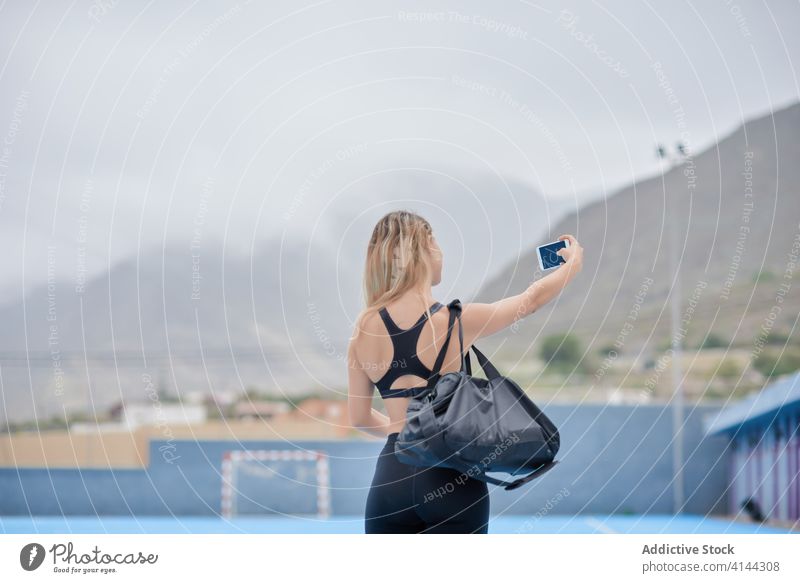 Sportliche Frau macht Selfie auf Sportplatz sportlich Smartphone Sportpark passen Athlet Sportlerin schlank Telefon Aktivität Lifestyle aktiv benutzend modern
