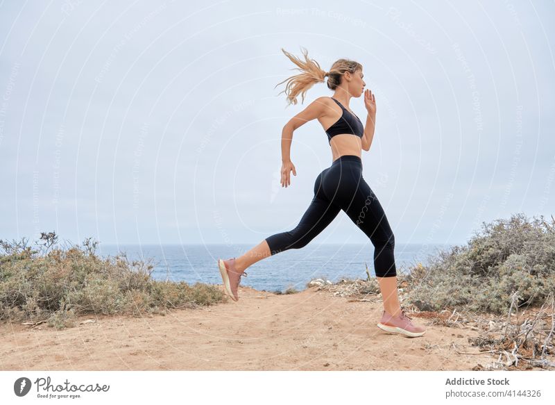 Junge sportliche Frau beim Training am Meer laufen Seeküste Fitness Sportlerin jung schlank Athlet Übung modern Wellness Wohlbefinden Gesundheit Lifestyle
