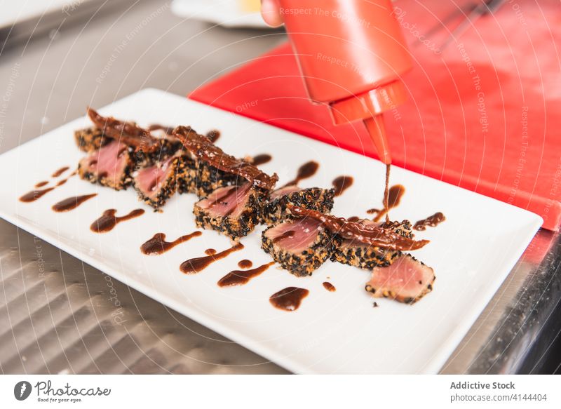 Nahaufnahme einer Thunfisch-Tataki-Platte, die mit Sauce angerichtet wird. Gesundheit Restaurant Essen zubereiten Lebensmittel Küchenchef Mahlzeit Abendessen