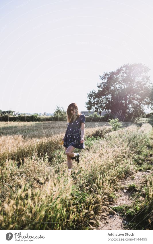 Fröhliche Frau geht am Feld entlang laufen Landschaft sorgenfrei Wochenende Sommer sonnig Freiheit heiter Gummi Stiefel Kleid Sonne Freude Wiese Natur Harmonie